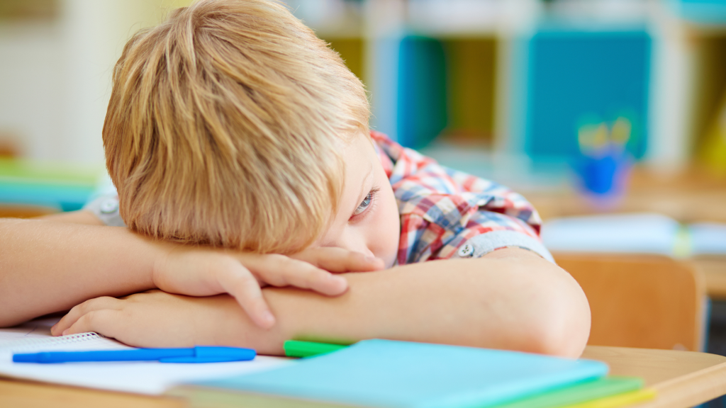 znudzone dziecko leży na biurku
