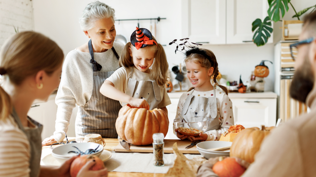 Dziadkowie i wnuczki wspólnie przygotowują dynię do Halloween. Ciepła, rodzinna atmosfera w kuchni. Halloween w rodzinnym stylu – radość i wspólne chwile
